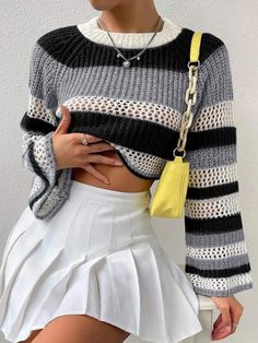 a woman wearing a blue striped sweater and white skirt with her hand on her hip