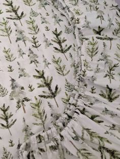 a close up view of the fabric with green leaves and branches printed on it, as seen from above