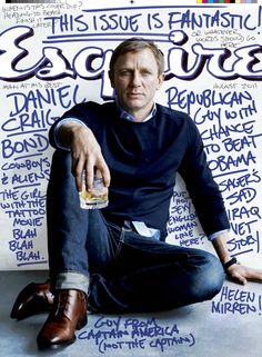 a man sitting on top of a magazine cover next to a white wall with writing