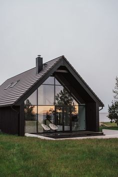 a black house with glass windows and grass