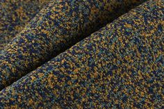 a blue and yellow tweed fabric with small speckles on the bottom half of it