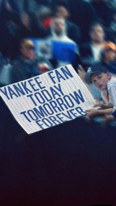 a fan holds up a sign in the stands at a baseball game, with words written on it