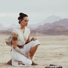 a woman sitting on top of a sandy field