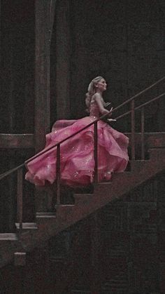 a woman in a pink dress is walking down the stairs