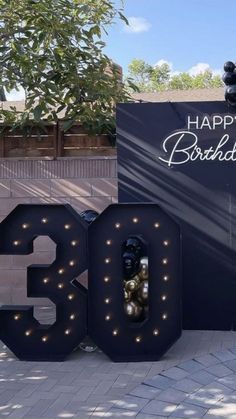 a large sign that says happy birthday with lights on it and balloons in the shape of numbers