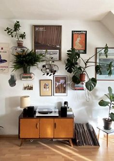 a living room with plants and pictures on the wall