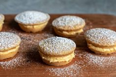 several powdered sugar covered pastries sit on a cutting board