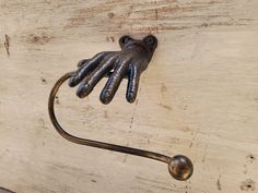 a hand that is attached to a hook on a wooden surface with it's hands