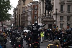 a group of bikers riding down the street in front of a statue on a horse