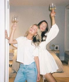 two women standing next to each other holding wine glasses