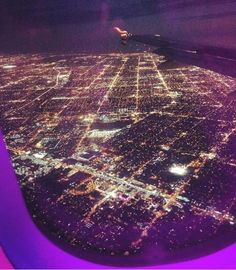 an aerial view of the city lights at night as seen from inside an airplane window