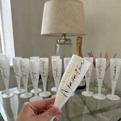 a person holding up a wine glass with the word happy written in gold on it