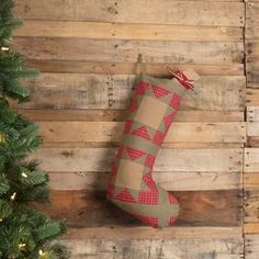 a christmas stocking hanging from the side of a wooden wall next to a tree