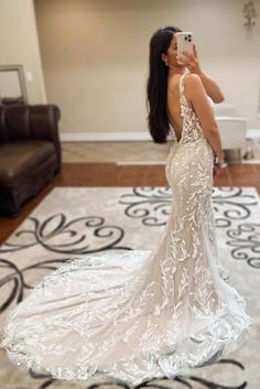 a woman taking a selfie in her wedding dress while standing on the floor next to a couch