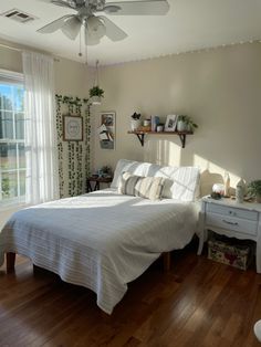 a bed sitting in a bedroom next to a window covered in white sheets and pillows