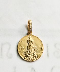 "This beautiful 18K gold vermeil Saint Mary Magdalene medal depicts her being \"Carried by Angels,\" as she was 7 times a day when she lived in La Sainte-Baume for thirty years in contemplation and prayer. The medal measures 20mm in diameter. The reverse is decorated with a lily flower.  In the Cave of La-Sainte-Baume there is a beautiful statue of Mary Magdalene raised up by angels. It is the work of L.J. Alexandre (c. 1878). Pilgrims come from all over the world to her cave to pray: \"Marie-Ma Yellow Gold Medallion For Commemoration, Yellow Gold Coin Pendant For Commemoration, 14k Yellow Gold Jewelry With Miraculous Medal, 14k Gold Miraculous Medal Jewelry In Gold, 14k Gold Jewelry With Miraculous Medal, Yellow Gold Miraculous Medal Jewelry, Commemorative Gold Charm Jewelry, Yellow Gold Round Miraculous Medal Jewelry, Commemorative Gold Jewelry With Charms