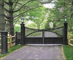 a gated driveway leading into a lush green park