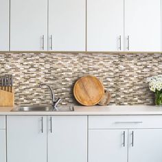 a kitchen with white cabinets and wooden cutting board