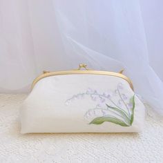 This hand-embroidered floral clasp bag is a useful product that you can carry your stuff with style. The hand-embroidered lily of the valley  gives it a beautiful retro look! The strap is removable, so you can use it as a cosmetic pouch or clutch bag. One bag, two styles! If you are looking for a special gift for her or their loved ones then you should definitely not miss this product. Please kindly note that actual product colors may vary from the colors shown on your monitor. You can choose th Spring Clutch Evening Bag As Gift, Spring Clutch Evening Bag, Spring Clutch Evening Bag For Gift, Spring Formal Clutch Pouch, Handmade Pouch Clutch For Spring, Spring Pouch Clutch As Gift, Spring Gift Pouch Clutch, Elegant Spring Clutch For Daily Use, Spring Wedding Clutch Bag