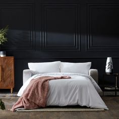 a bedroom with black walls and white bedding