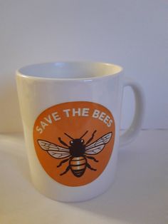 a white coffee cup with a bee on the front and save the bees sticker on the side