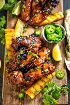 grilled chicken wings with pineapple salsa on a cutting board next to sliced jalapenos and lime wedges