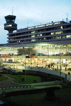 an airport terminal lit up at night with people walking around the building and onlookers