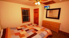 a bed room with a neatly made bed and a flat screen tv on the wall