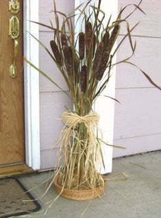 a vase with dried plants in front of a door