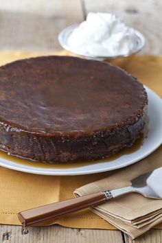 a chocolate cake sitting on top of a white plate next to a knife and fork