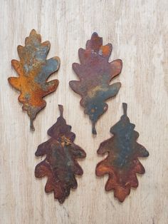 three rusted metal leaves sitting on top of a wooden table