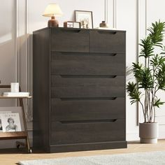 a tall wooden dresser sitting on top of a floor next to a potted plant