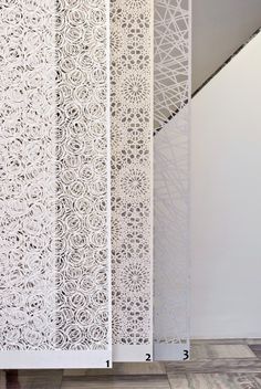 an intricately designed screen in the corner of a room with wooden floors and white walls