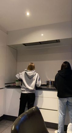 two people standing in a kitchen preparing food