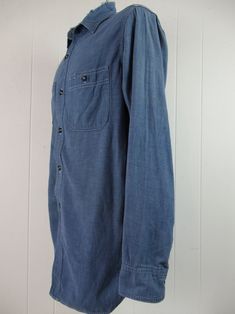 "Vintage 1940s work shirt. Made of cotton chambray. Color is medium blue. Has a button down front, button cuffs, two chest pockets and triple stitched seams. Hercules work clothing by Sears. Size medium. Actual measurements are: 43\" at the chest 42\" at the waist 16\" shoulder seam to shoulder seam 25\" shoulder seam to cuff 32\" overall length In good condition with a worn through collar and some minor paint spots." Pre-washed Cotton Button-up Shirt, Unstructured Indigo Button-up Shirt, Washed Blue Collared Shirt With Snap Buttons, Blue Pre-washed Long Sleeve Shirt, Blue Long Sleeve Pre-washed Shirt, Indigo Button-down Shirt For Work, Indigo Shirt With Buttons For Workwear, Washed Blue Chambray Shirt With Buttons, Vintage Unstructured Shirt With Pockets