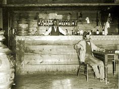 an old photo of a man sitting at a bar