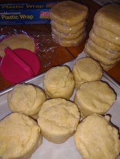 a bunch of doughnuts that are on top of a baking sheet and some plastic wrap