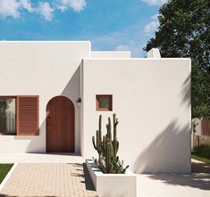 a white house with wooden shutters and cactus in the front yard on a sunny day