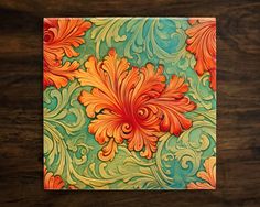 an orange and green floral design on a wooden table with wood grains in the background