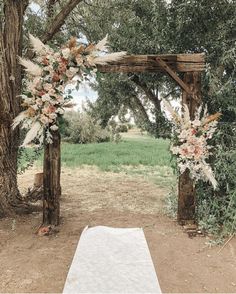 an outdoor wedding ceremony setup with flowers and greenery on the arch, surrounded by trees