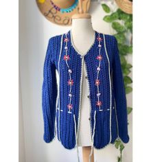 a mannequin wearing a blue knitted cardigan with flowers on the front