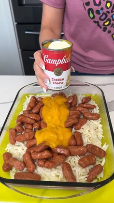 a woman holding a can of campbell's cheddar cheese sauce over rice and beans