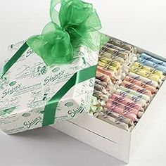 an open gift box filled with lots of different colored candies and wrapped in green ribbon