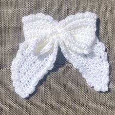 a white crocheted bow on top of a piece of cloth