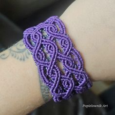 a close up of a person's arm wearing a purple beaded wristband