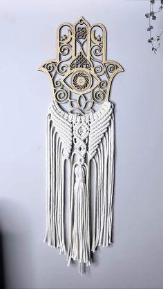 the hamsa wall hanging is made out of wood and has fringes on it