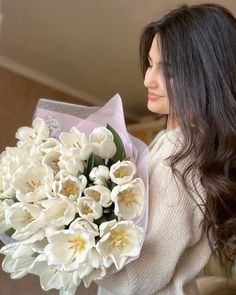 a woman holding a bouquet of white flowers