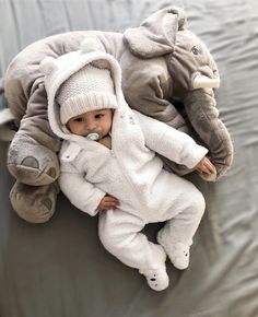 a baby is laying on top of an elephant pillow with its mouth in it's mouth