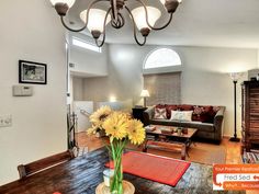 a dining room table with yellow flowers in a vase on it and a couch behind it