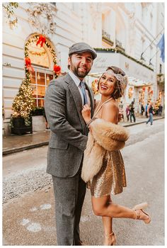 a man and woman standing next to each other in front of a building with christmas decorations